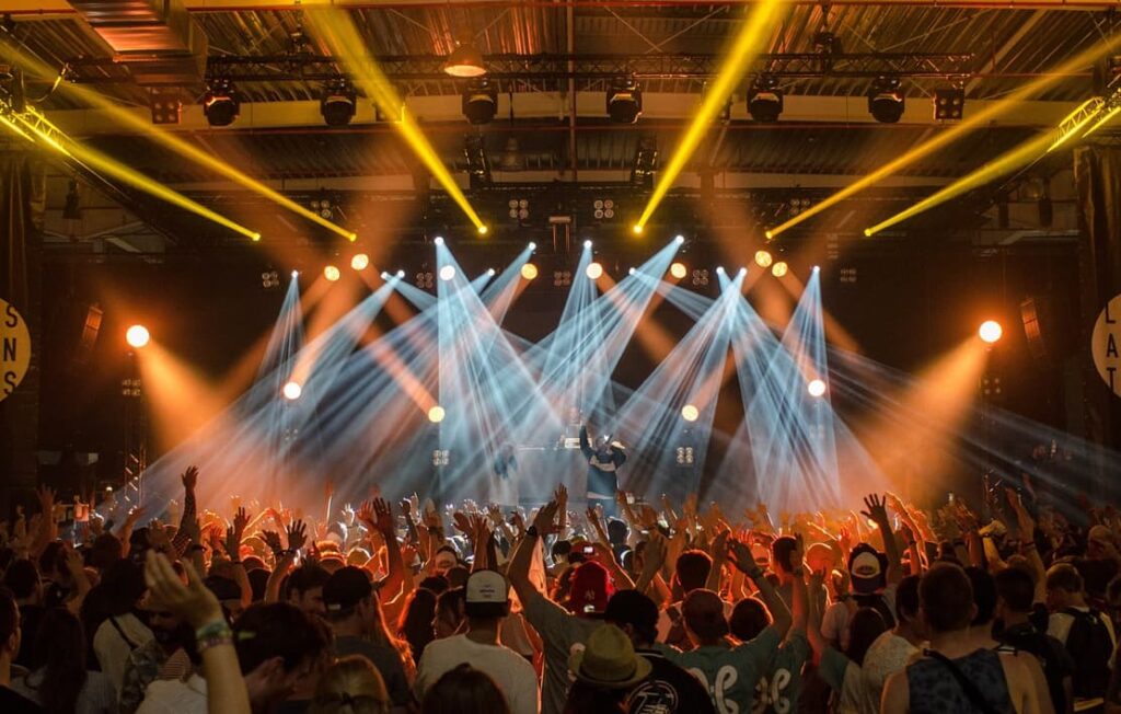 A concert with a crowd of people enjoying the performance under dynamic stage lights