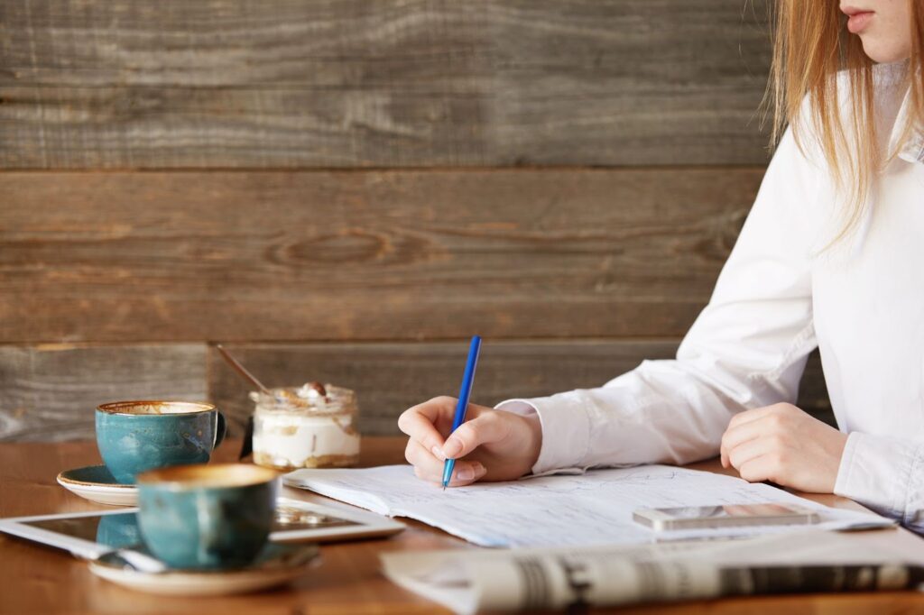 Young red-haired woman in cafe writing a letter