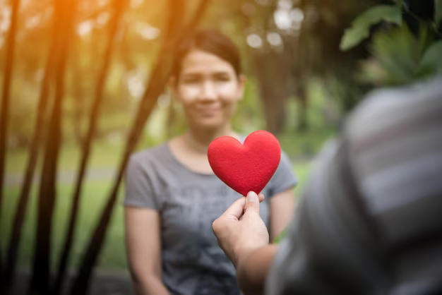 A man holds a heart-shaped figurine opposite a girl